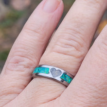 Load image into Gallery viewer, This titanium ring is small yet durable. It is 6mm wide and shows the unique ashes next to the bright colors of the green opals.

